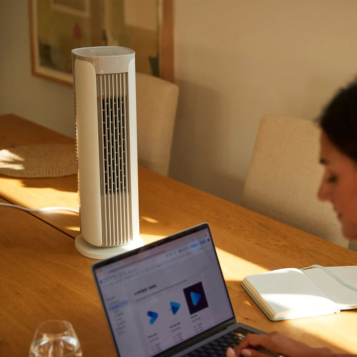 MeacoFan Sefte 19" Tower Fan on a dining table beside a woman working at a laptop